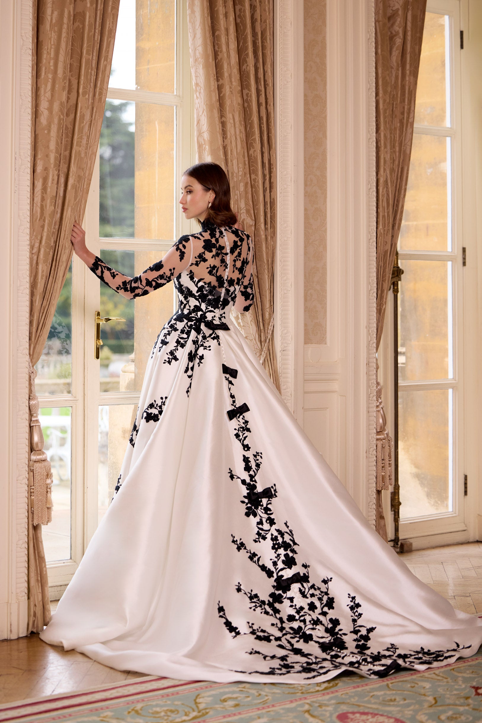 straight strapless neckline A-line dress with black lace with dramatic train and long black gloves and bows with black lace long sleeve topper