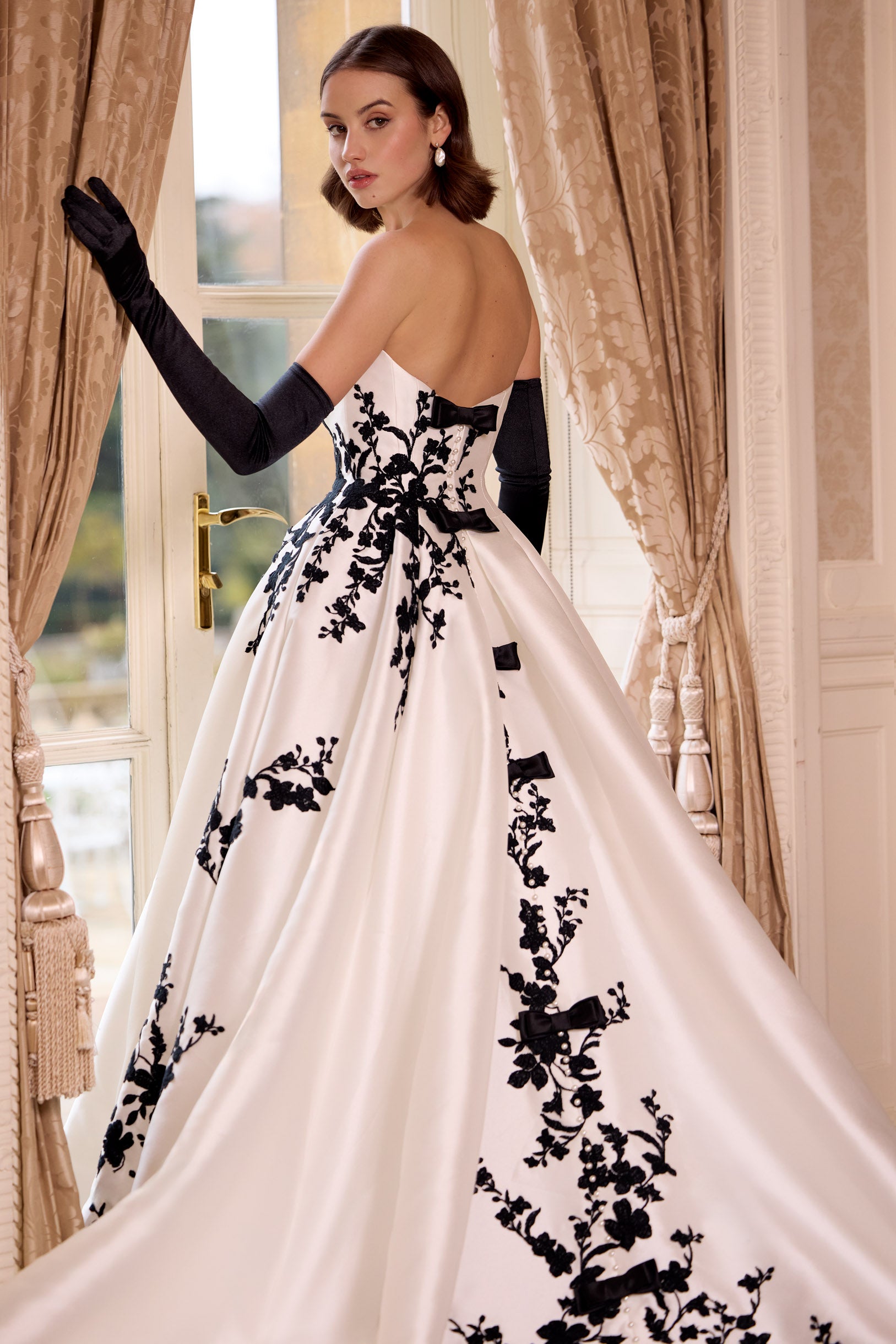 straight strapless neckline A-line dress with black lace with dramatic train and long black gloves and bows