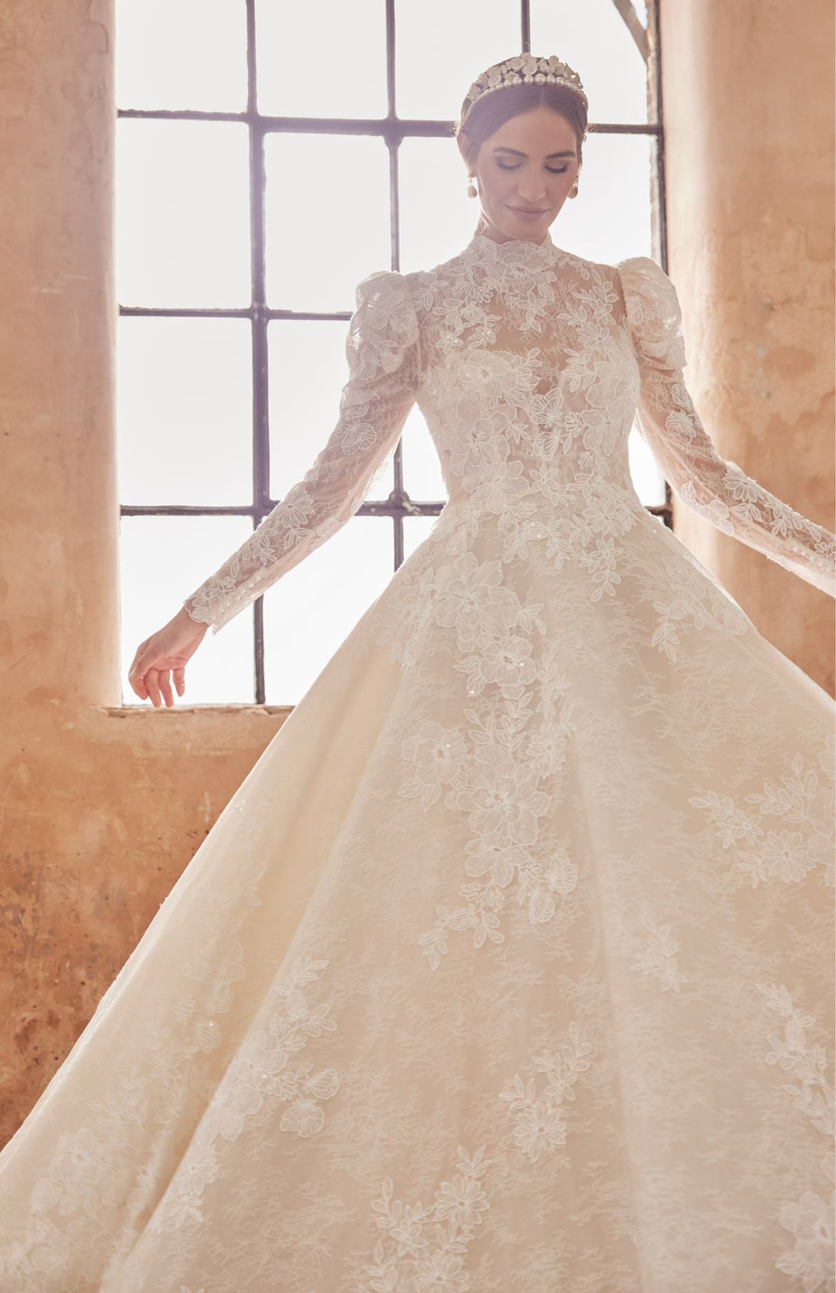 High-neck luxury lace A-line gown with romantic long puffed sleeves. Finest embroidered lace with a full skirt. Keyhole back and full length covered buttons on train.