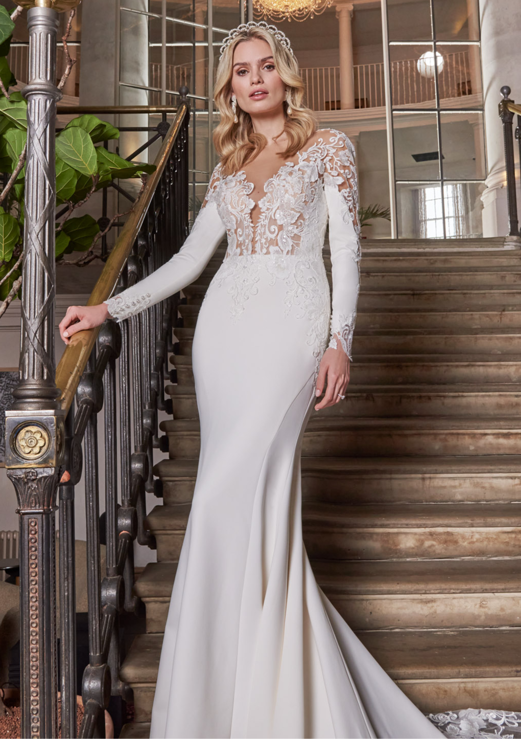 A luxury crepe sculpted dress, lace double tiered train with detailed lace appliqué. A timeless open v-neckline with cut-out sleeves with divine cuff detail