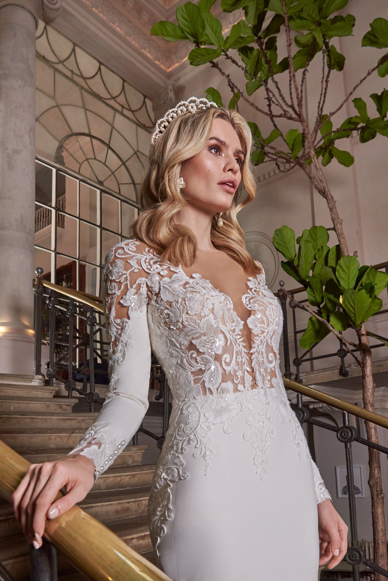 A luxury crepe sculpted dress, lace double tiered train with detailed lace appliqué. A timeless open v-neckline with cut-out sleeves with divine cuff detail