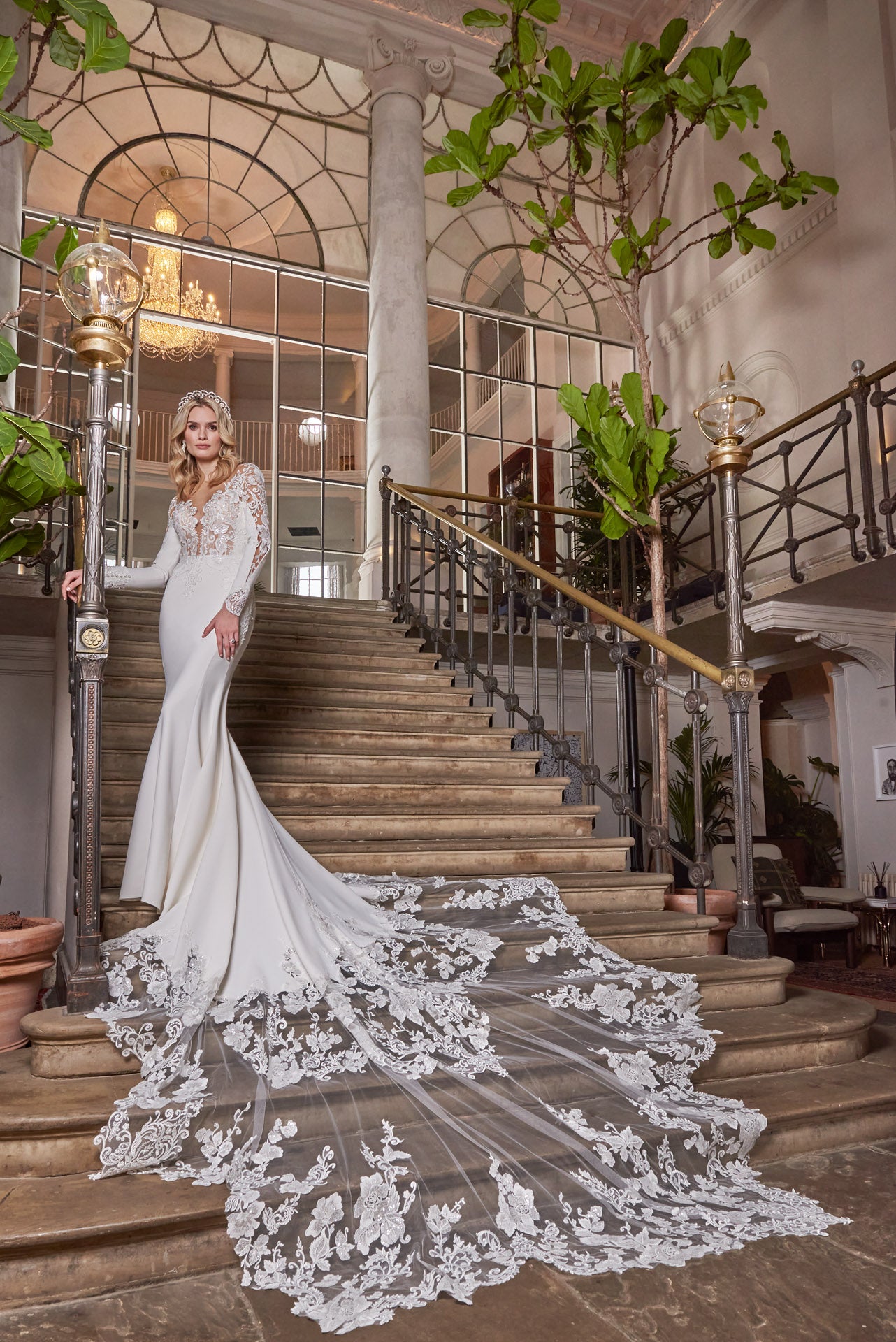 A luxury crepe sculpted dress, lace double tiered train with detailed lace appliqué. A timeless open v-neckline with cut-out sleeves with divine cuff detail