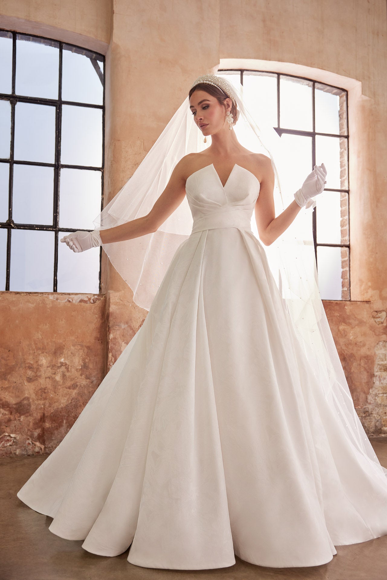 Embossed jacquard A-Line gown with strapless neckline and full skirt. Wrap around waist and pearl buttons along the back into the train.