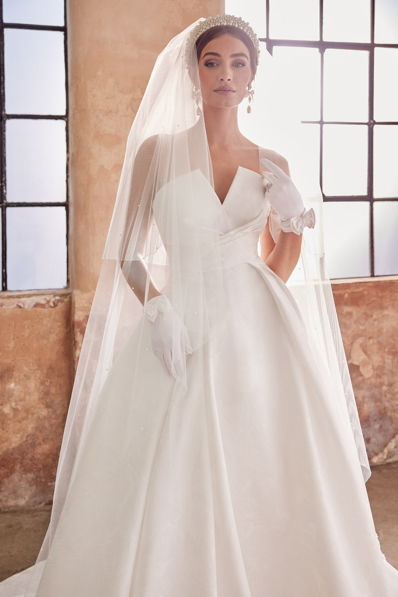 Embossed jacquard A-Line gown with strapless neckline and full skirt. Wrap around waist and pearl buttons along the back into the train.