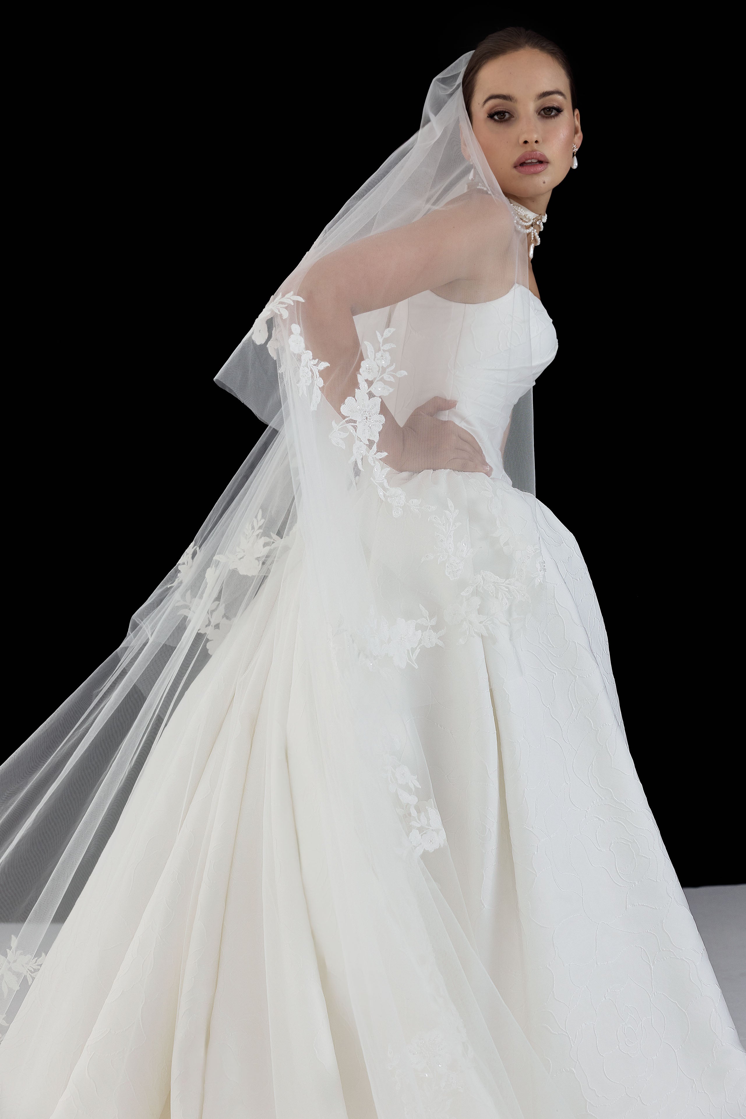 strapless cat eye neckline with sculptural structured pleated bodice and a basque waist and full A-line ballgown skirt with wedding veil