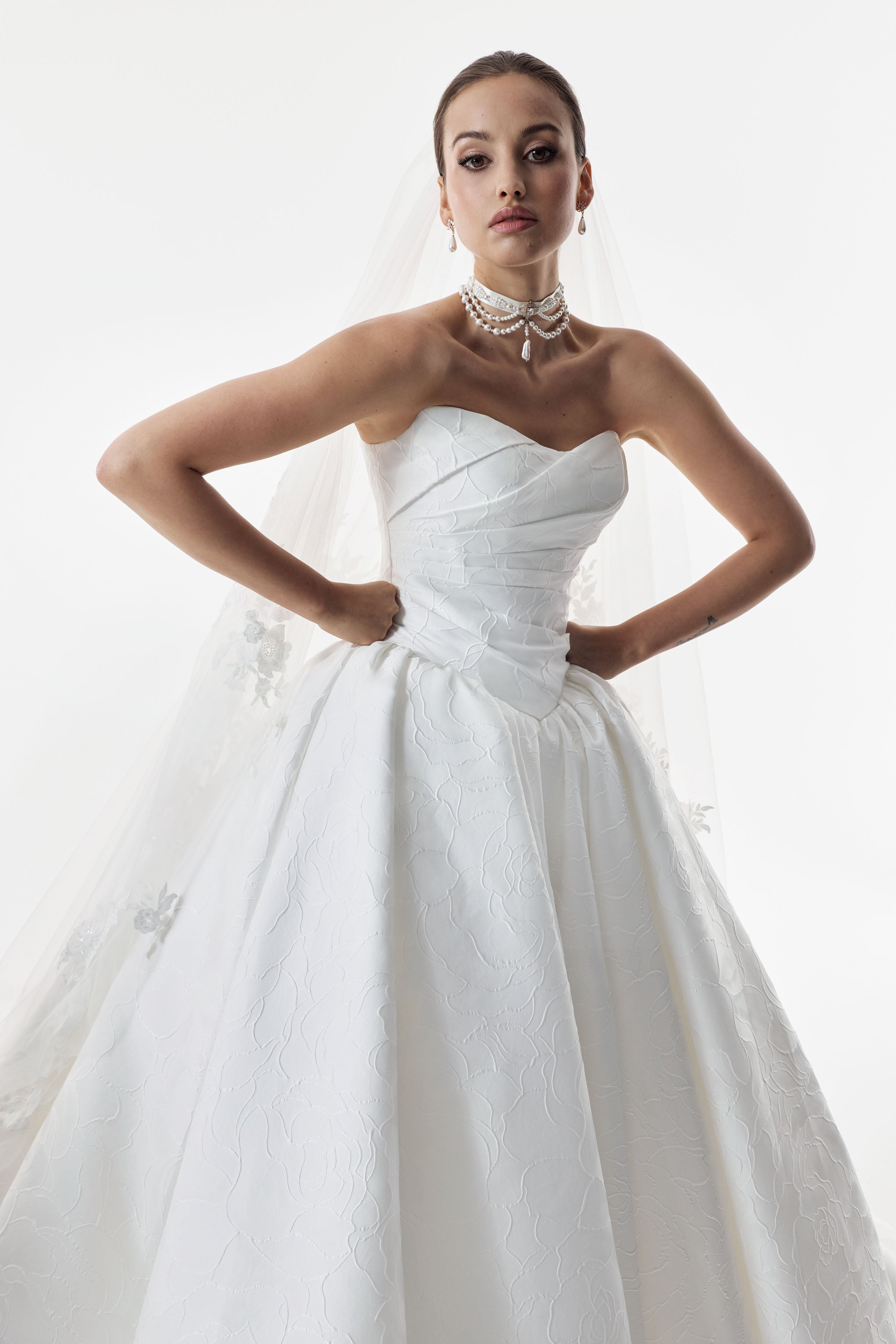 strapless cat eye neckline with sculptural structured pleated bodice and a basque waist and full A-line ballgown skirt with wedding veil