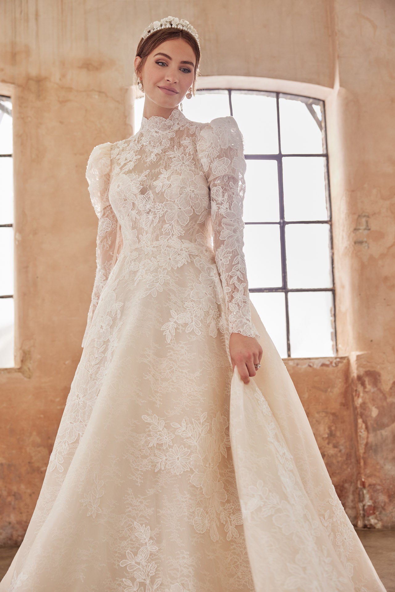 High-neck luxury lace A-line gown with romantic long puffed sleeves. Finest embroidered lace with a full skirt. Keyhole back and full length covered buttons on train.