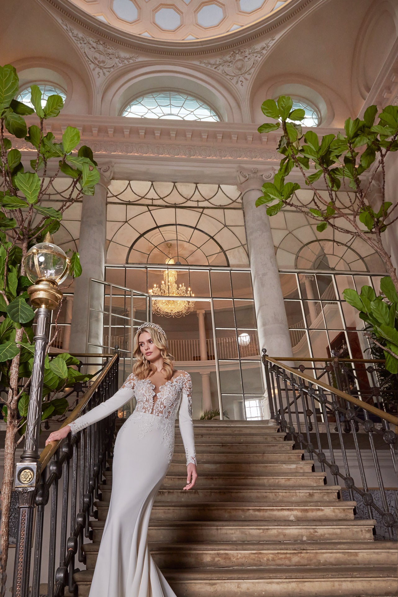 A luxury crepe sculpted dress, lace double tiered train with detailed lace appliqué. A timeless open v-neckline with cut-out sleeves with divine cuff detail
