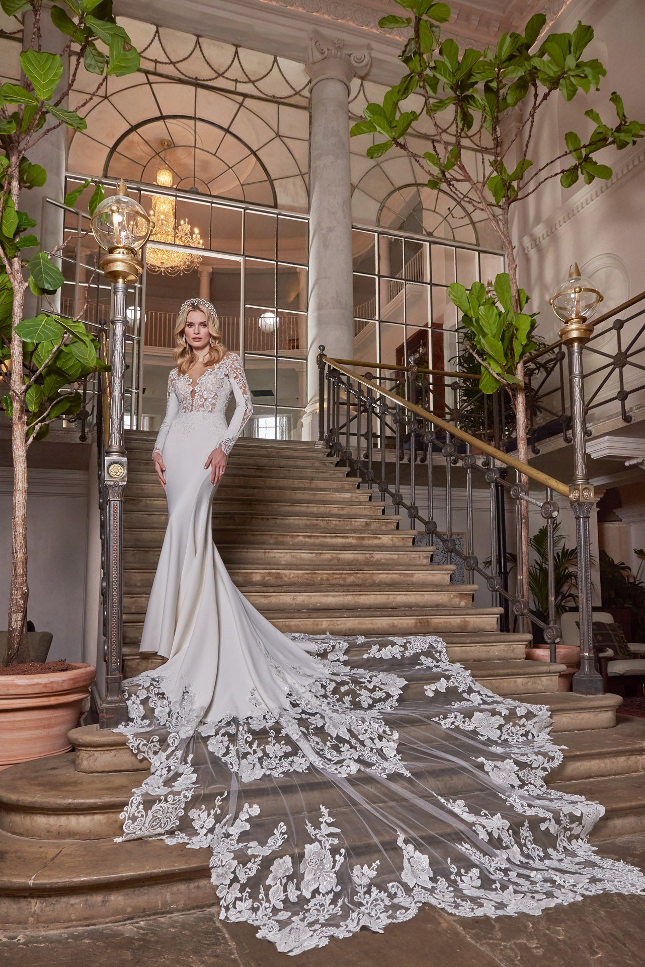 A luxury crepe sculpted dress, lace double tiered train with detailed lace appliqué. A timeless open v-neckline with cut-out sleeves with divine cuff detail